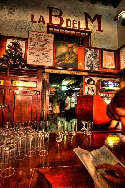 Interno del bar La Bodeguita con bancone in legno, bicchieri e luce ambrata calda
